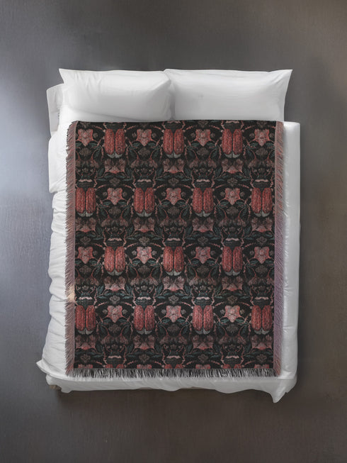 Luxurious woven cotton throw blanket featuring symmetrical scarab beetle pattern in terracotta on black background with white fringe detail. Perfect as gothic wall tapestry, dark academia decor, or cottagecore blanket for bedroom or living room.